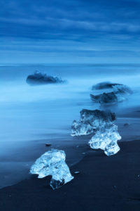 Diamond Beach, pieces of ice on the beach with icebergs in the background Diamond Beach, pieces of ice on the beach with icebergs in the background
